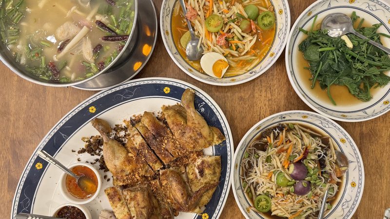 อาหารเต็มโต๊ะ ไก่ย่าง ส้มตำ ผักผัด และต้มยำปลา