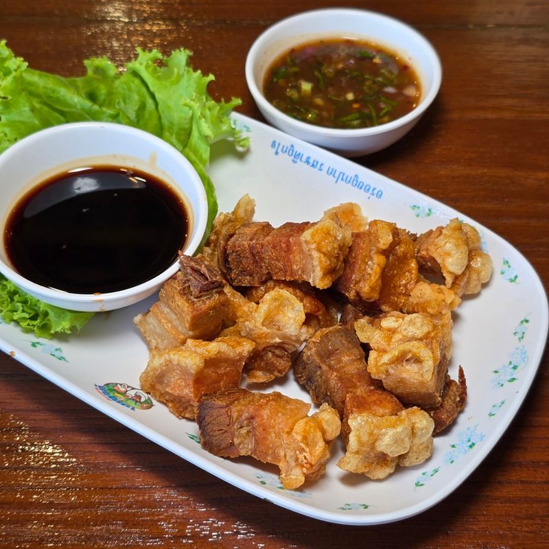 หมูสามชั้นทอดกรอบหั่นชิ้น วางคู่น้ำจิ้มสีเข้มและน้ำจิ้มพริก